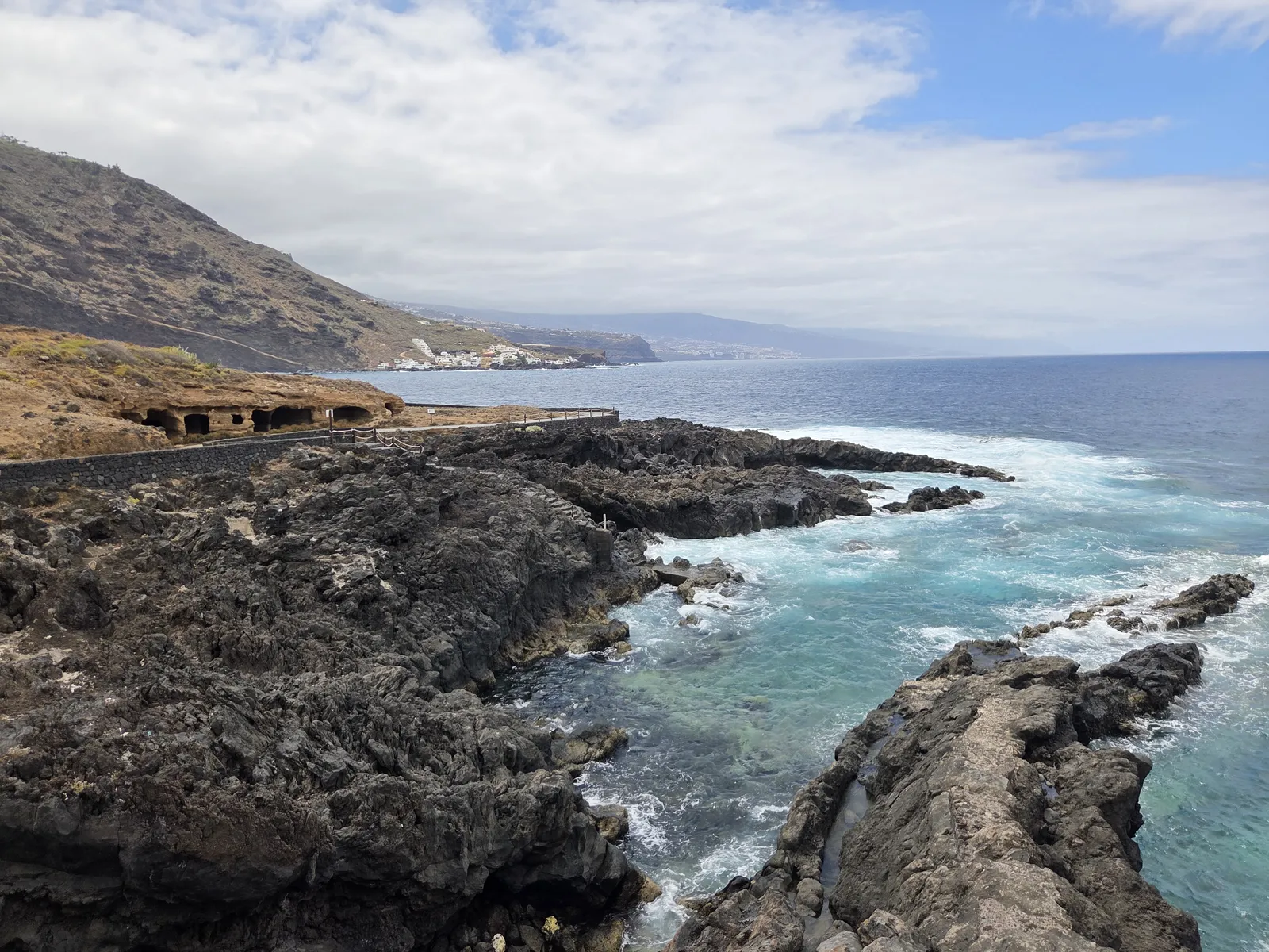 Black volcanic rocks surrounding a turquoise inlet beneath the cliffs of El Sauzal