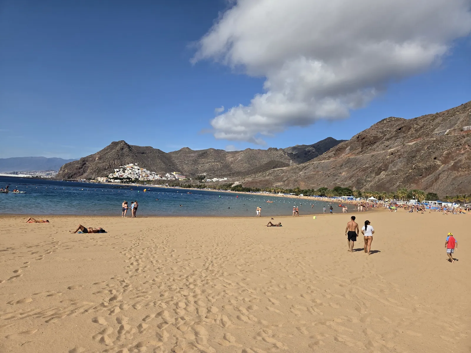 Wide golden sand at Las Teresitas with beachgoers, calm water and brown mountain slopes