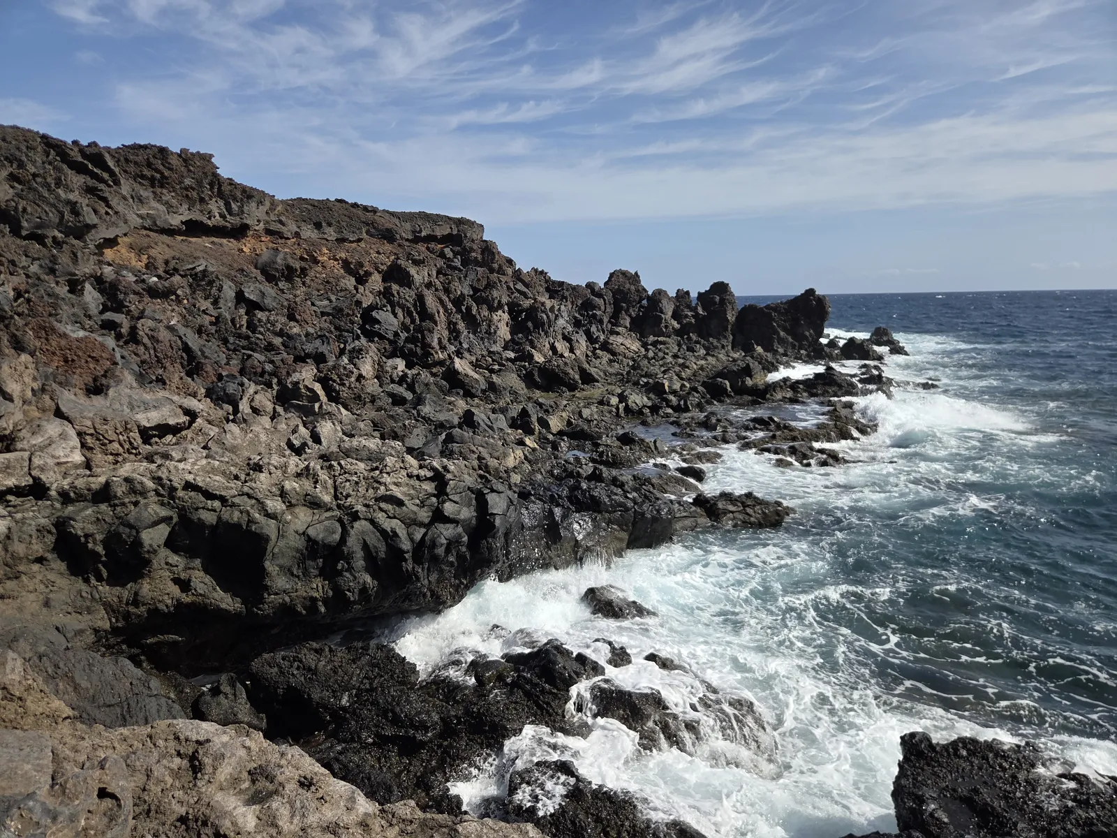 Atlantic waves breaking against jagged black lava on the coast of Malpaís de Güímar