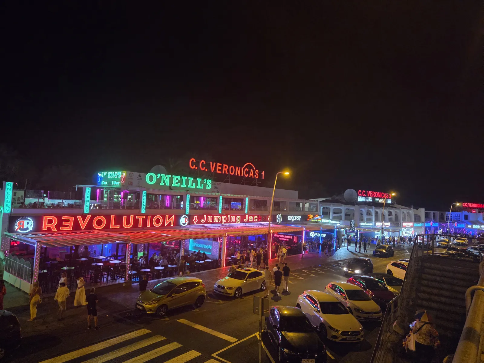 Illuminated bars at the Verónicas complexes with pedestrians and taxis at night
