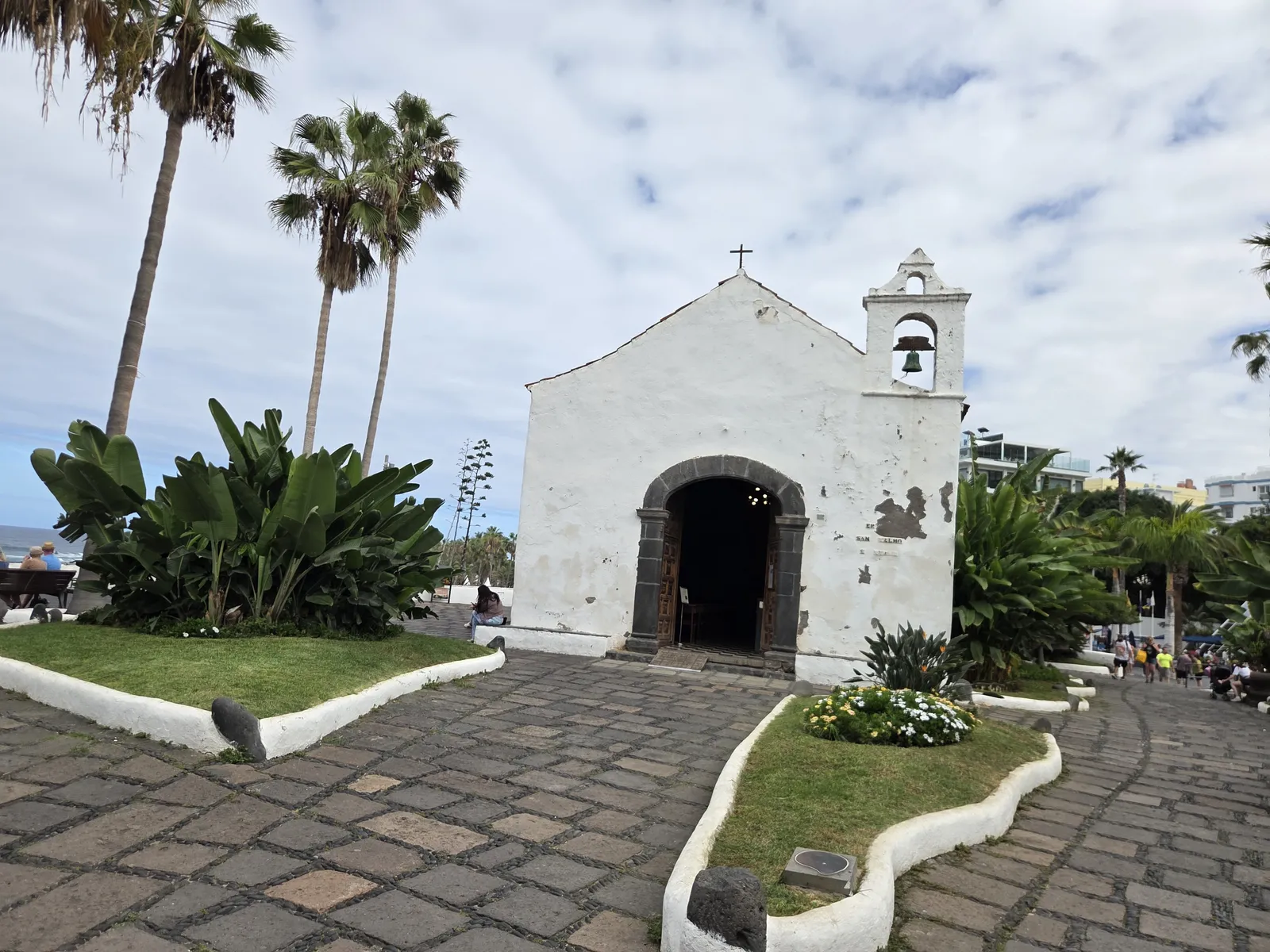 Whitewashed Ermita de San Telmo with a small bell gable, stone doorway and surrounding palms