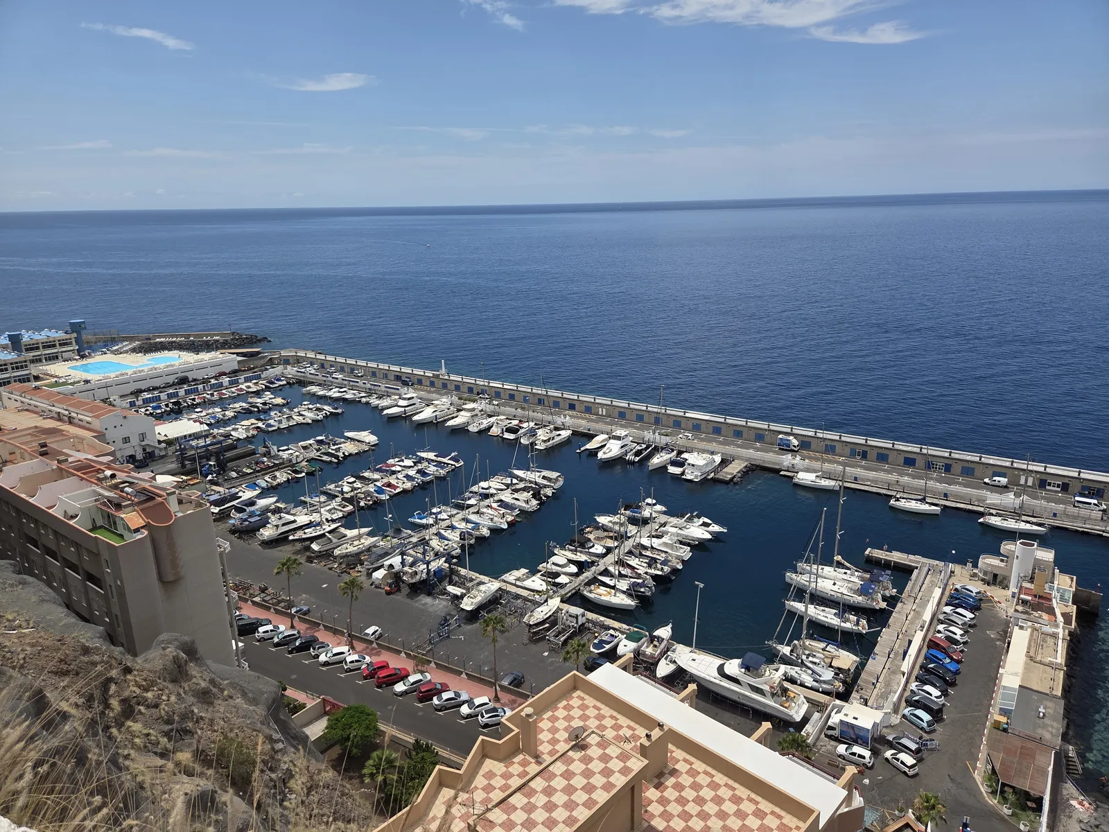 Rows of moored boats inside Radazul marina, enclosed by a long breakwater