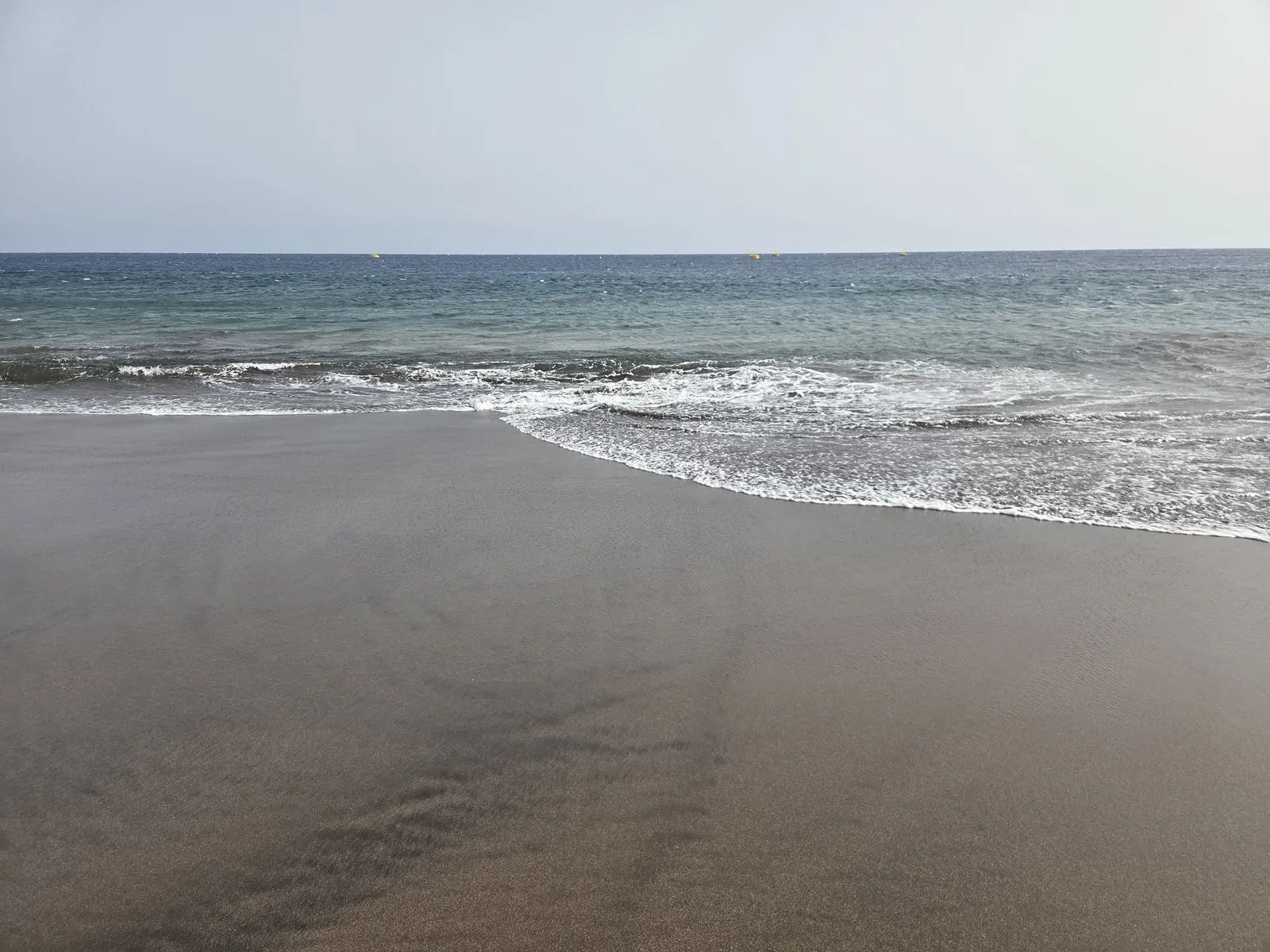 Small Atlantic waves washing over smooth wet sand at La Tejita Beach